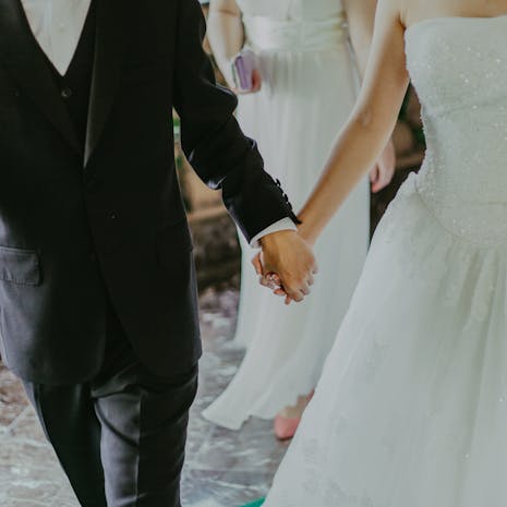 Woman Wearing White Wedding Gown Holding Hands With Man While Walking